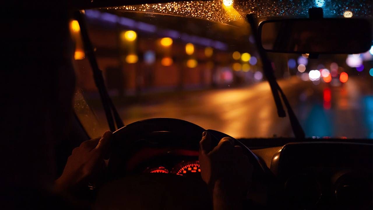 An over the shoulder shot of an older adult driving at night while struggling with night blindness. Next Avenue