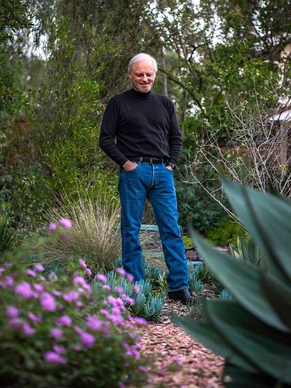 An older adult walking on a trail outside in a garden. Next Avenue