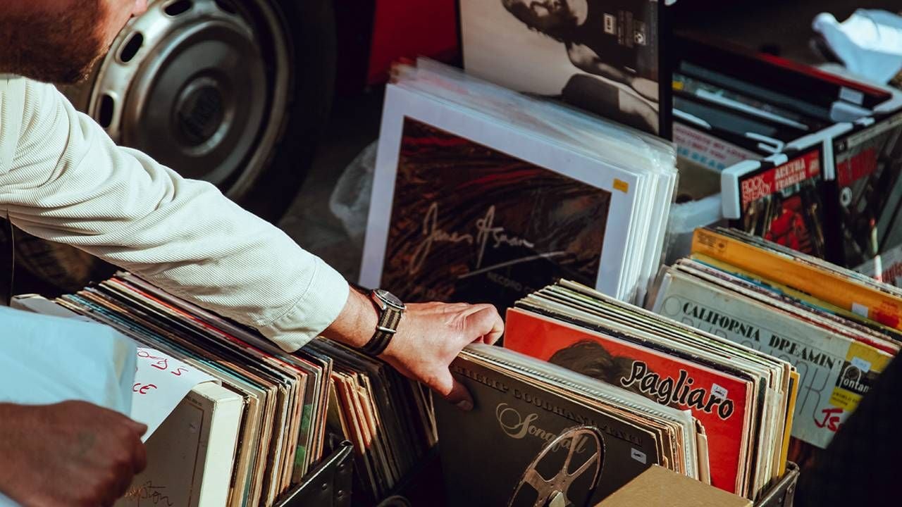 A person looking through a pile of records at a yard sale. Next Avenue, sell unwanted items