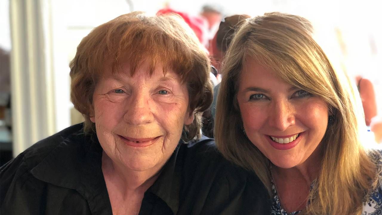 An older adult and her adult child smiling together while sitting outside. Next Avenue, resources for dementia caregivers