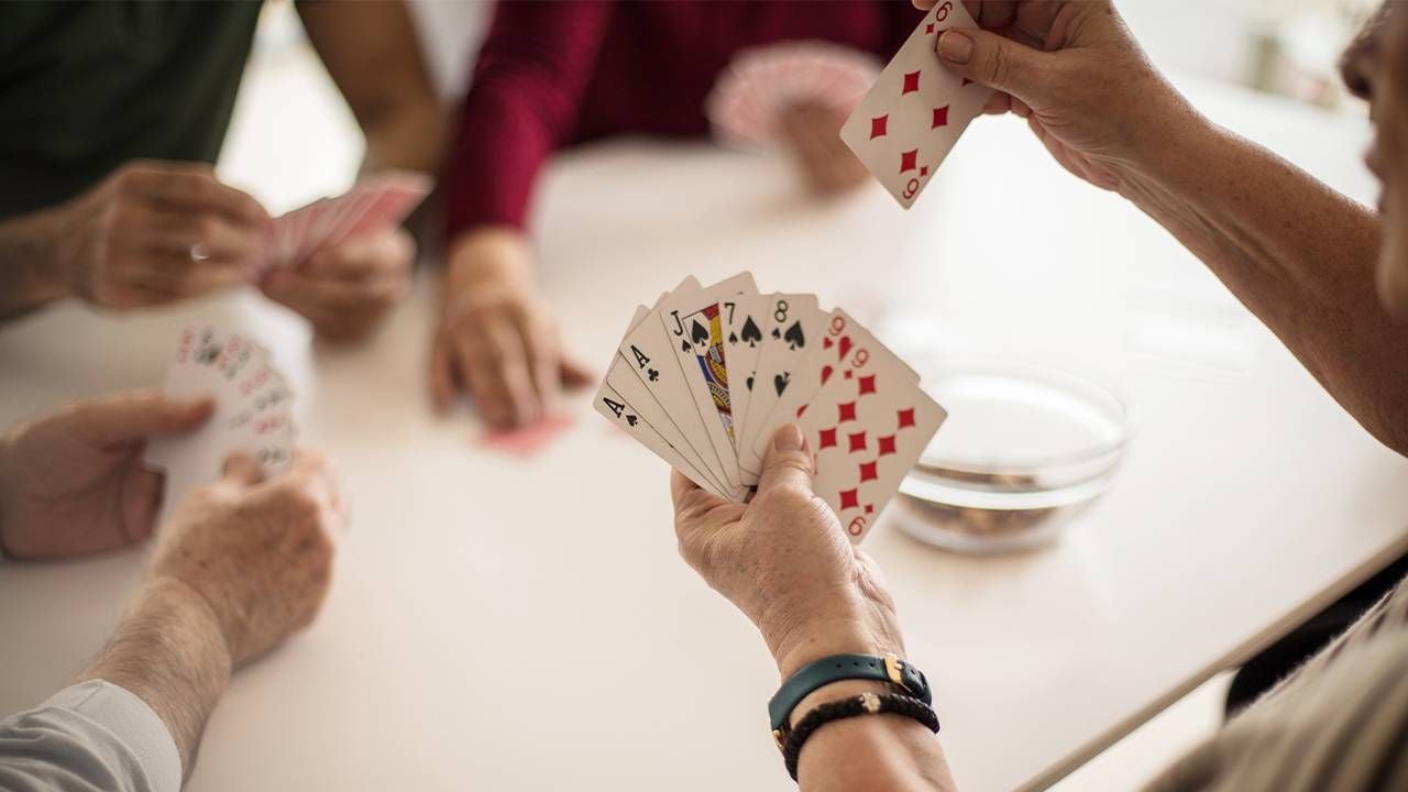 A group of friends playing cards during game night. Next Avenue, extroverts social isolation