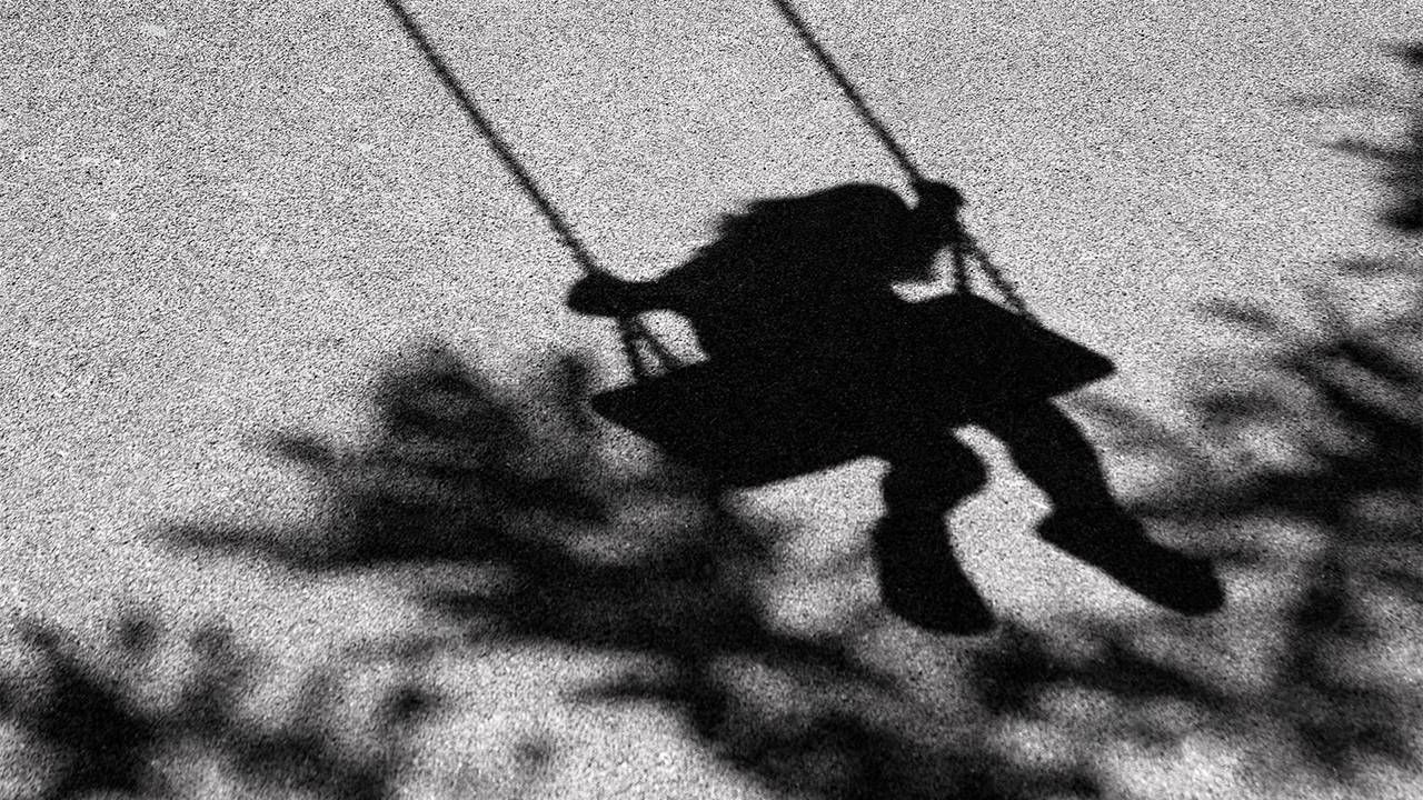 A black and white photo of a silhouette of a schoolgirl on a swing. Next Avenue, childhood bully, adults deal with childhood trauma