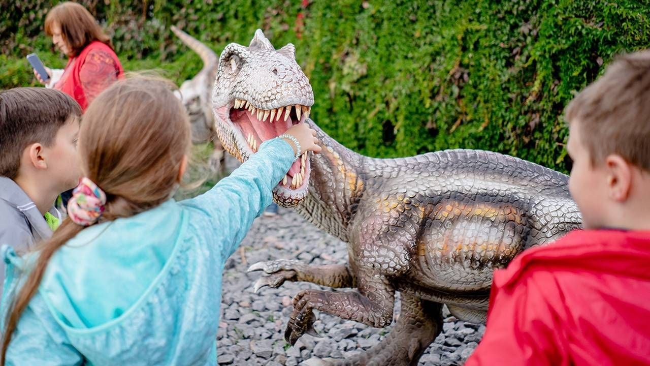 Children playing with a life-like dinosaur statue. Next Avenue, children's museums, activities to do with grandchildren