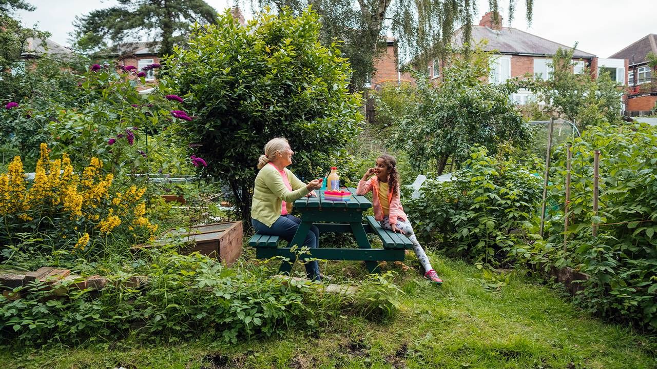 A grandmother eating gluten free food with her granddaughter on a picnic table. Next Avenue, celiac disease help