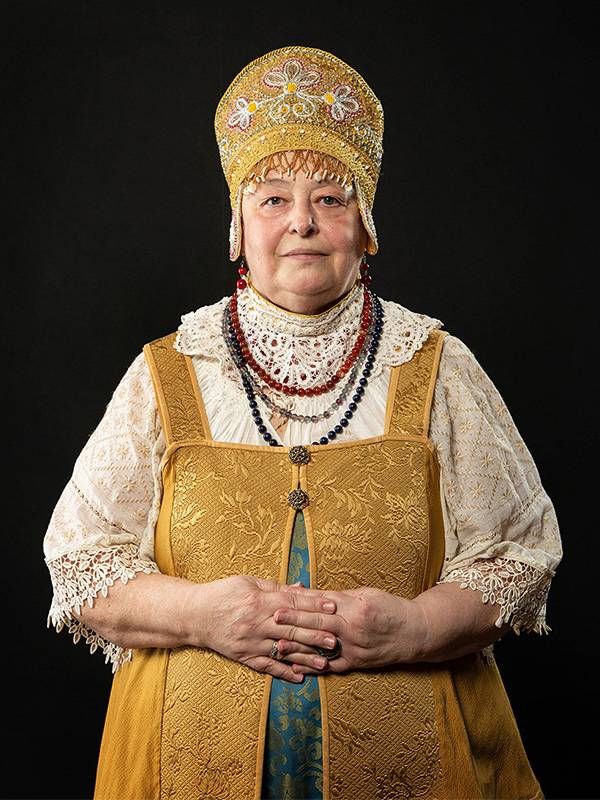A woman wearing traditional garb smiles. Next Avenue, Russian Ukrainian elders