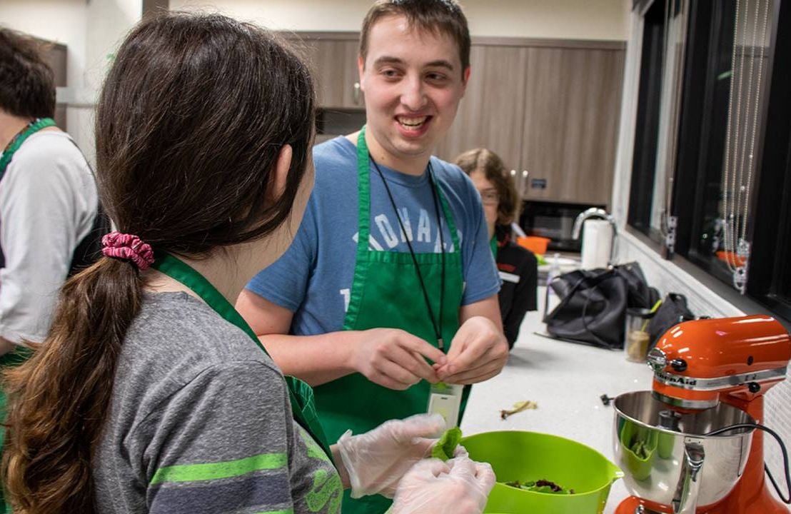 A group of people cooking together in a large kitchen. Next Avenue, housing, intellectual and developmental disabilities, IDD