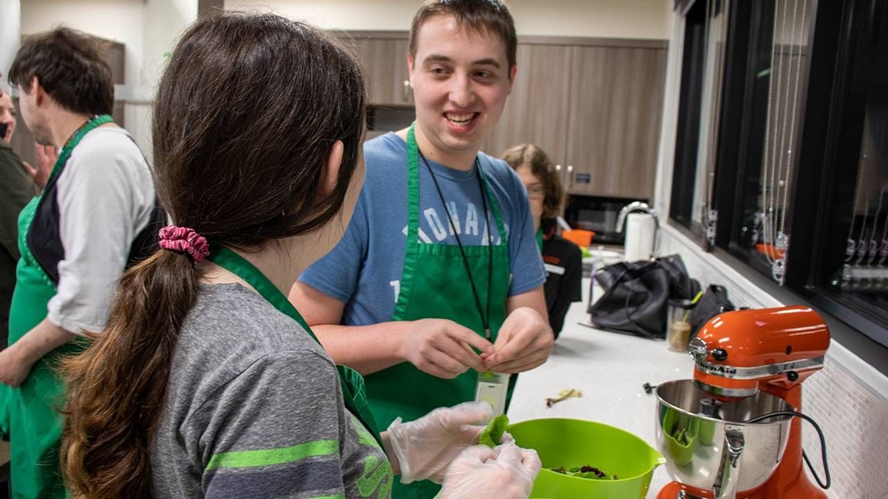 A group of people cooking together in a large kitchen. Next Avenue, housing, intellectual and developmental disabilities, IDD