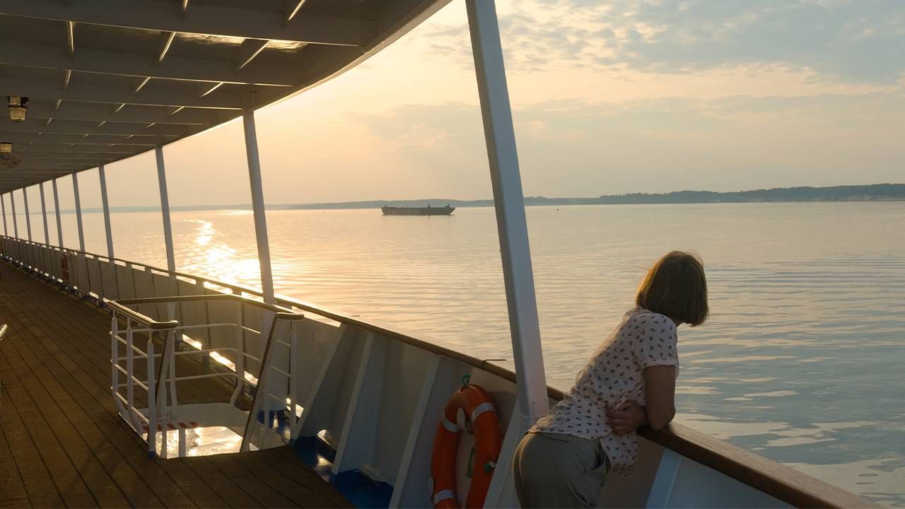 A woman looking out while on a grief cruise. Next Avenue, splatter paint, grief yoga, grief cruise