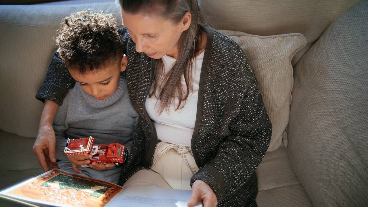 A grandmother reading a book to her grandchild. Next Avenue, kindness benefits, health