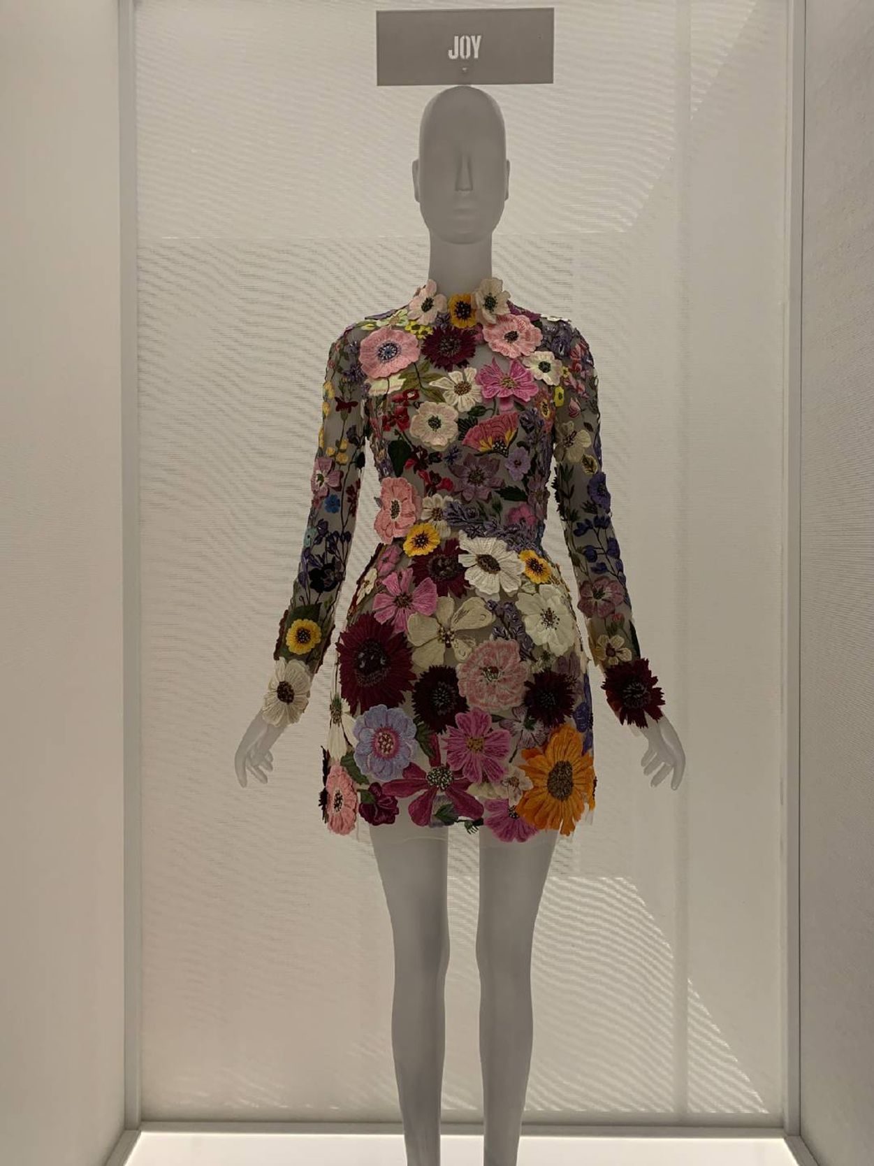 A mannequin wearing a dress of embroidered flowers.