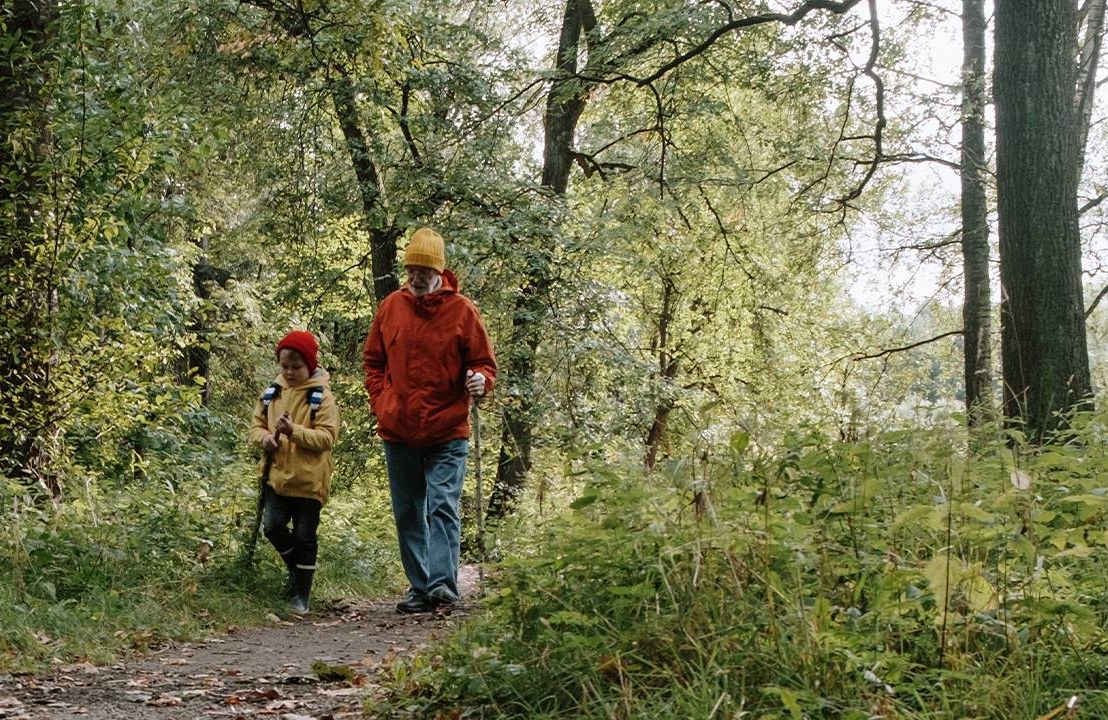 An older man walking in the woods with his grandchild. Next Avenue, overcoming age bias