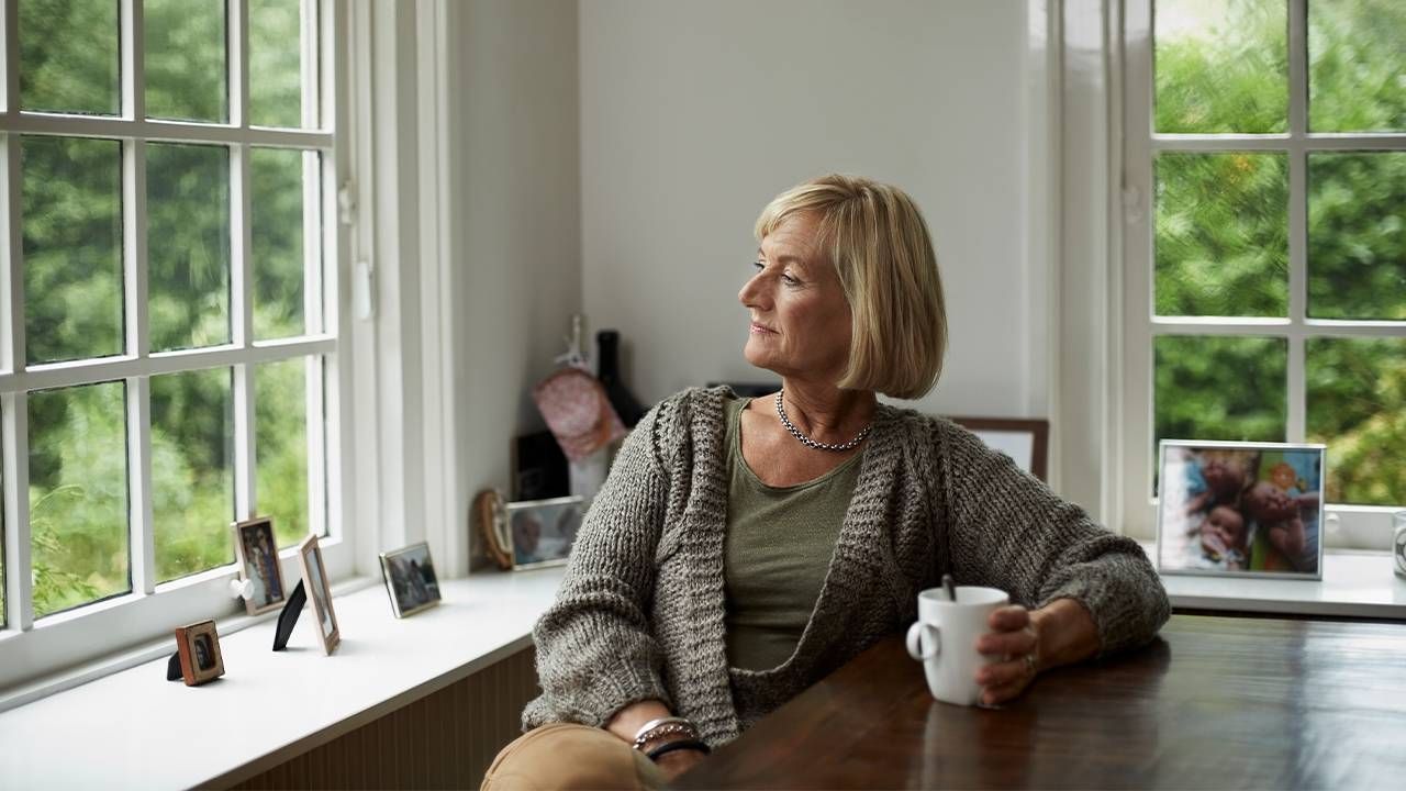 An older woman looking out a window. Next Avenue, Grief healing mental health