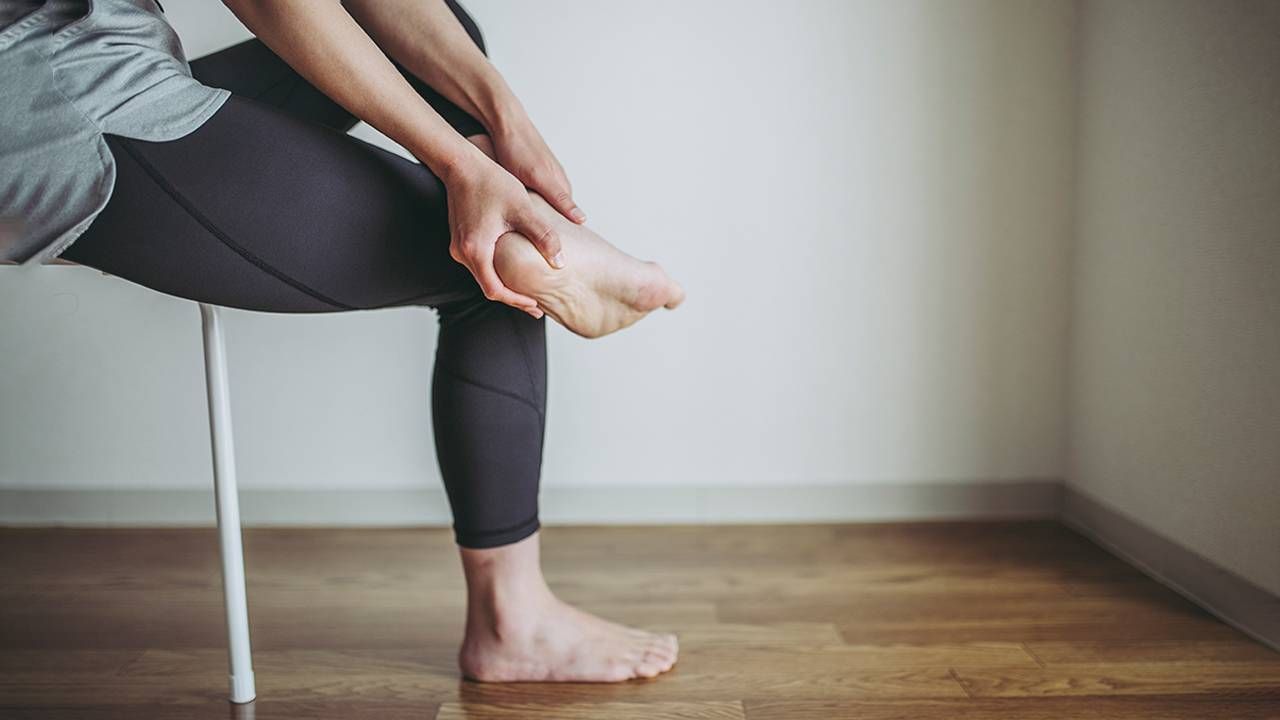 A woman rubbing the heel of her foot. Next Avenue, plantar fasciitis pain foot heel arch