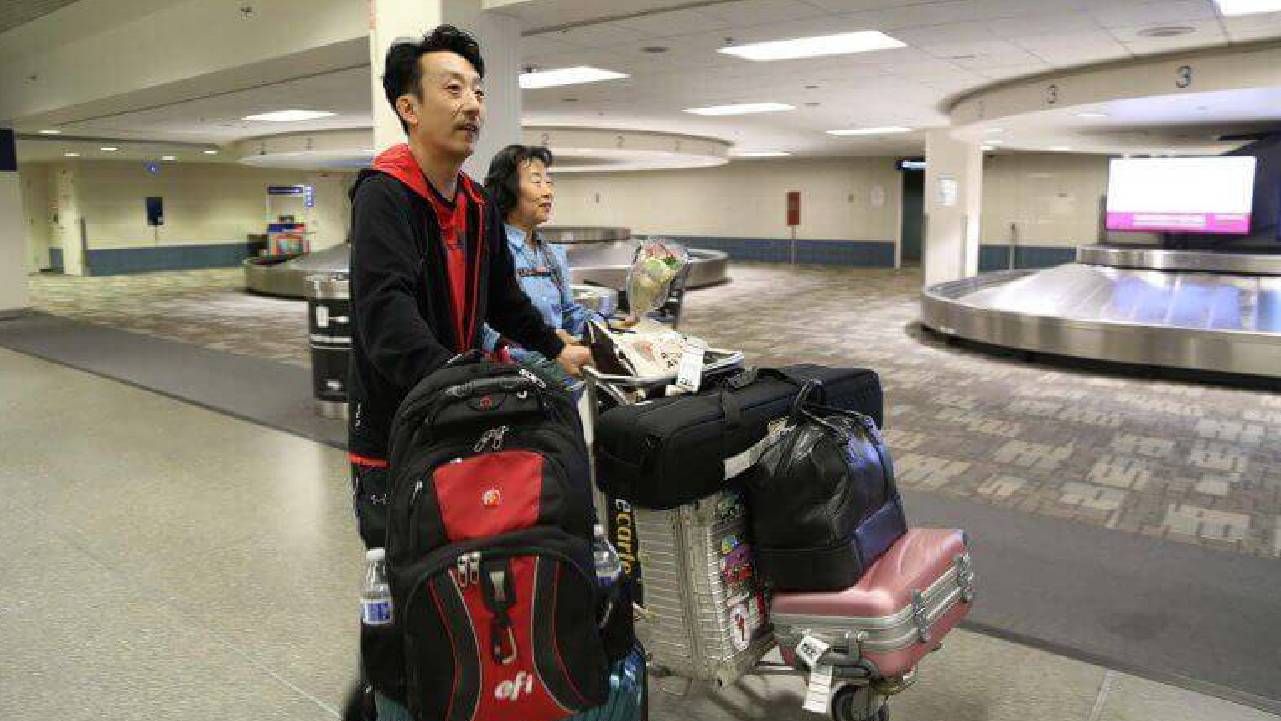 Two people lugging suitcases through an airport. Next Avenue, adoptee story, memorial day