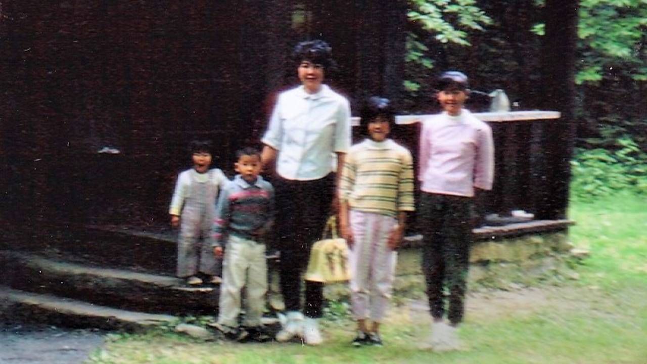 An old photo of a family standing outside a cabin. Next Avenue, family road trip
