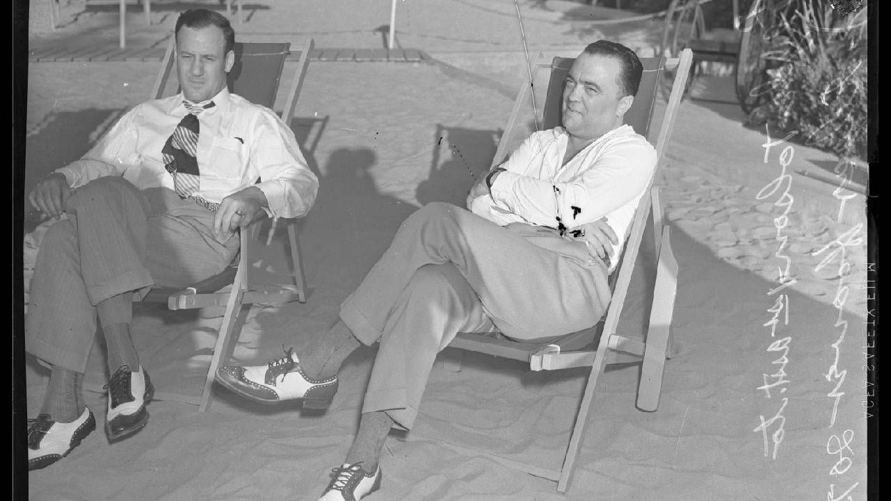 Two men sitting on patio chairs on a sandy beach. Next Avenue, LGBTQ history, Washington d.c.