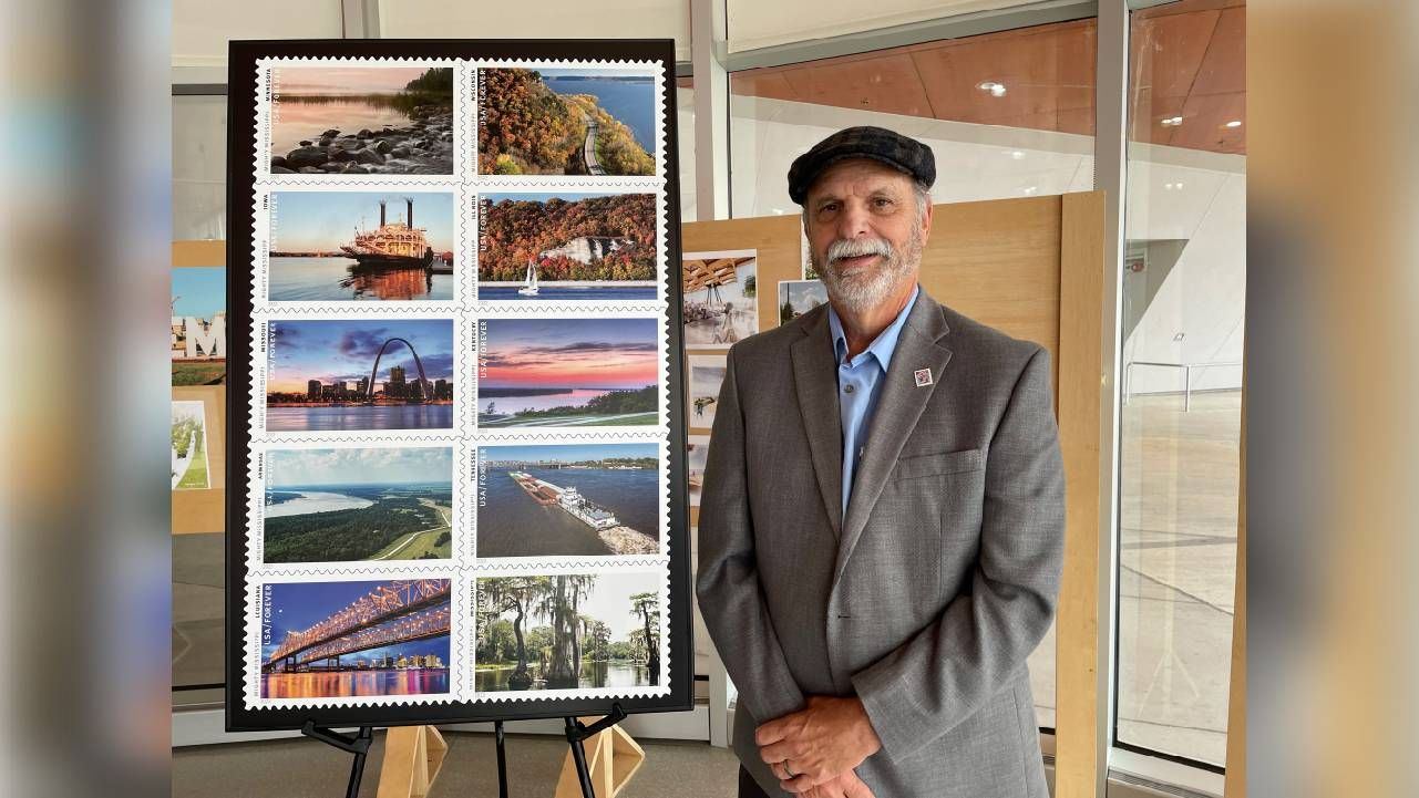 A man posing next to iterations of his photos as stamps. Next Avenue, retirement stories, becoming an artist in retirement