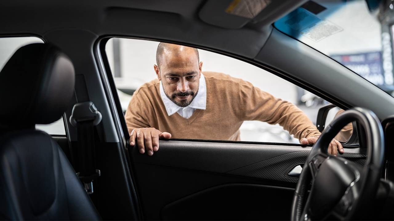 An older adult looking at a new car in a dealership. Next Avenue, tips on buying new car