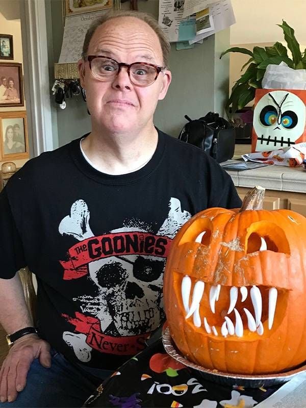 An older adult posing next to a jack-o'-lantern. Next Avenue, care for down syndrome adults, alzheimer's