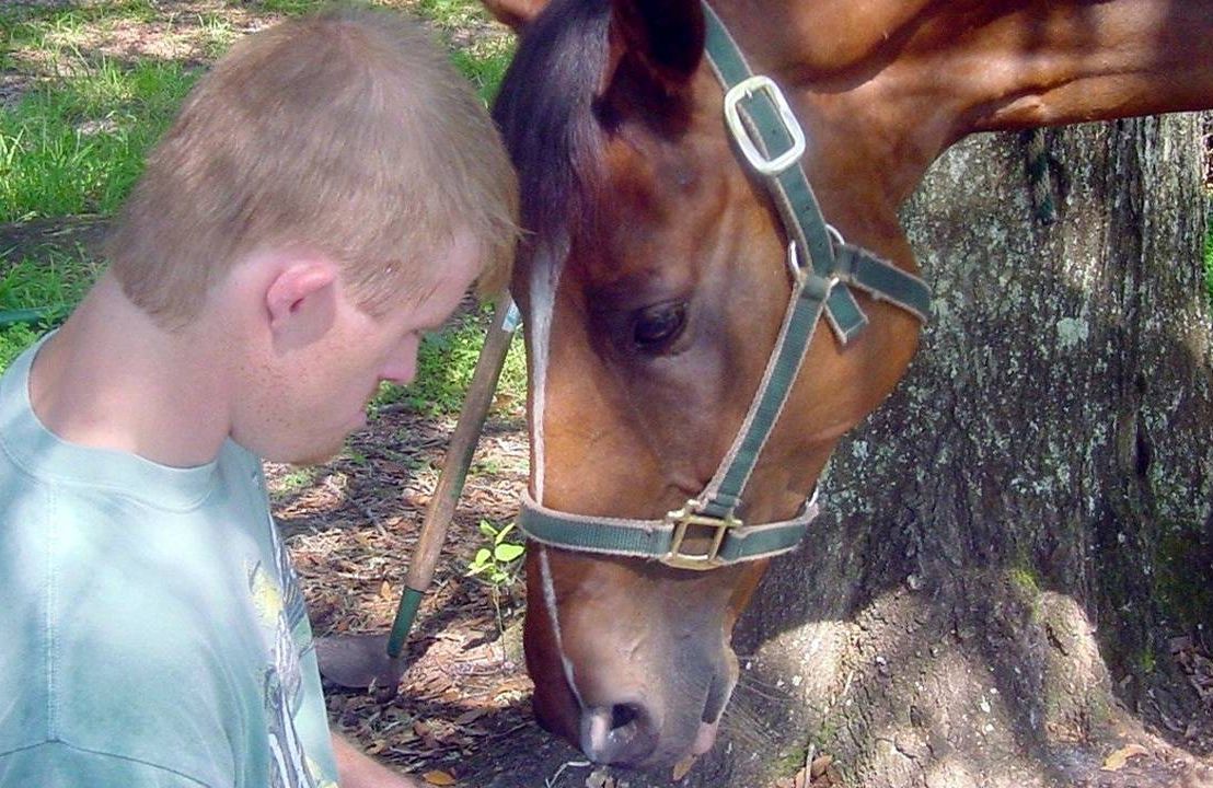 An adult touching his forehead to a horse's forehead. Next Avenue, care for down syndrome adults, alzheimer's