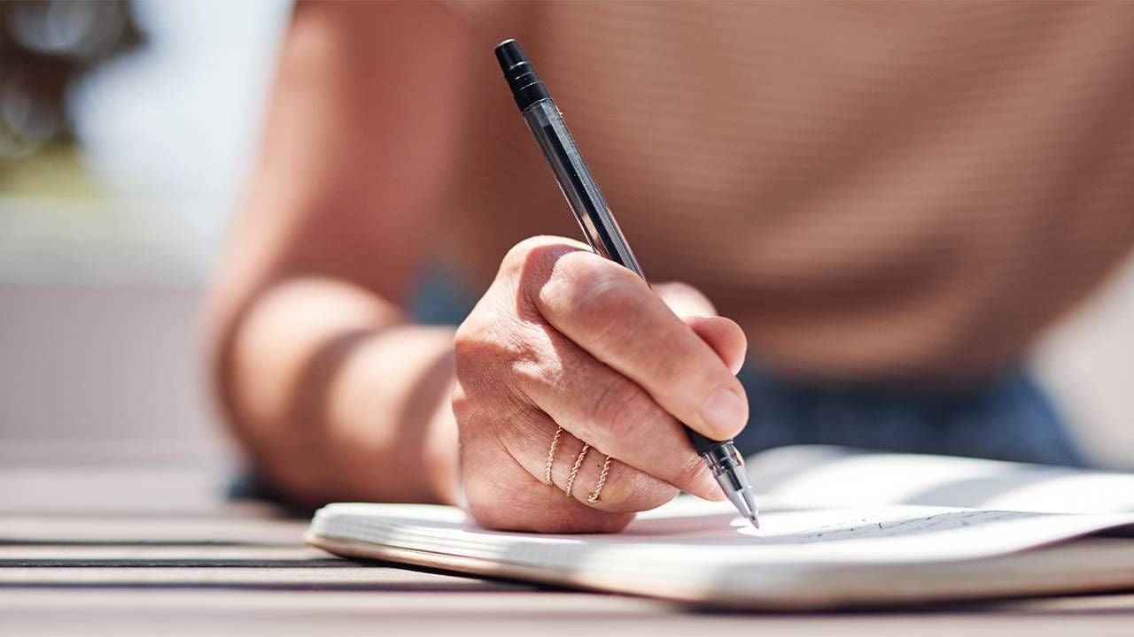 Close up of an older woman's hand writing with a pen. Next Avenue, gay in heterosexual relationship