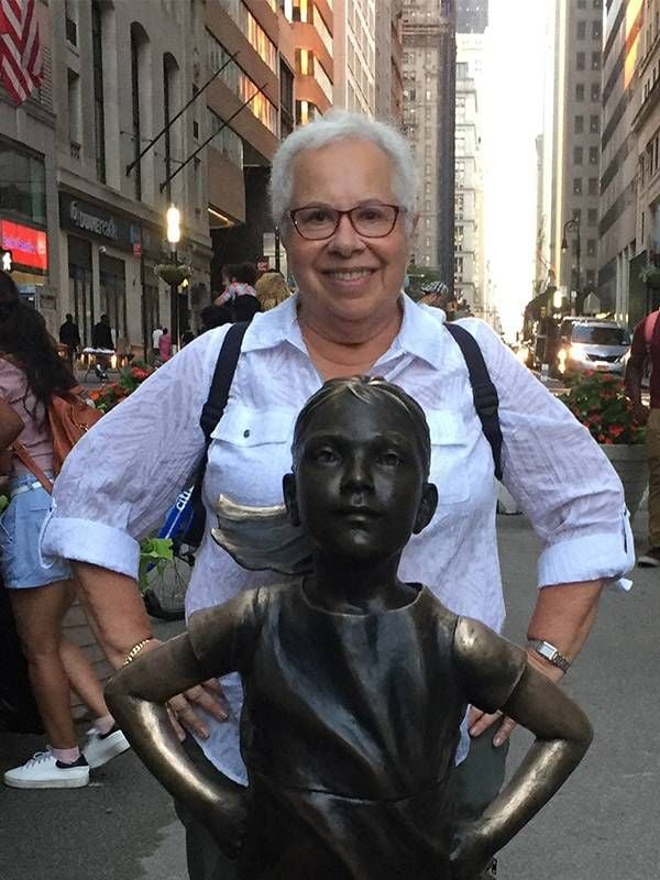 An older woman standing behind a brass statue. Next Avenue, gay in heterosexual relationship