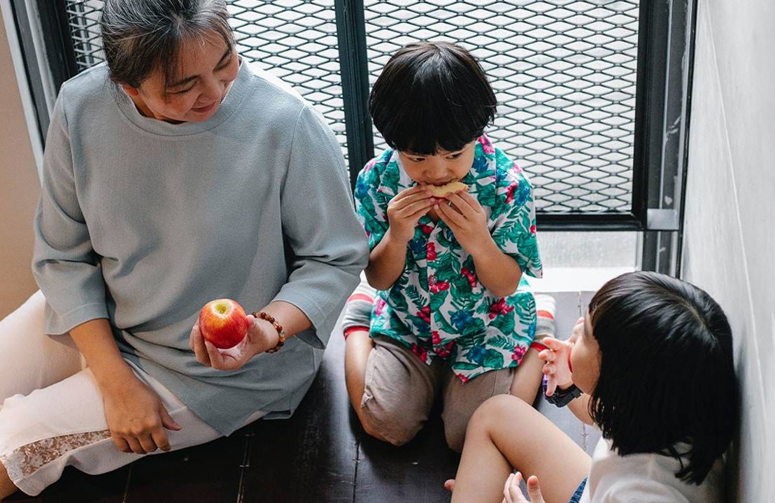 A grandmother eating snacks with her grandchildren. Next Avenue, intergenerational households