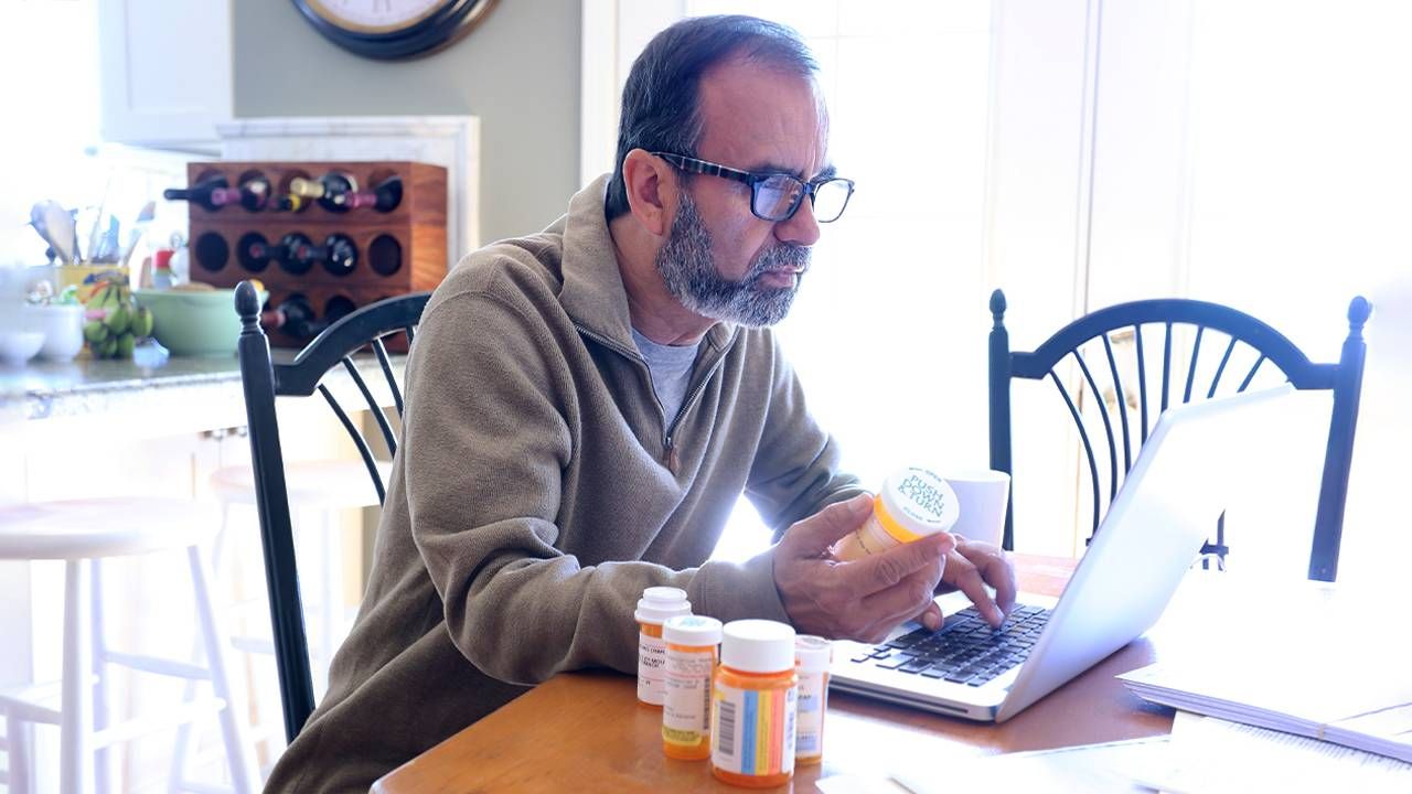 An older adult holding prescription medication bottles. Next Avenue, online pharmacy