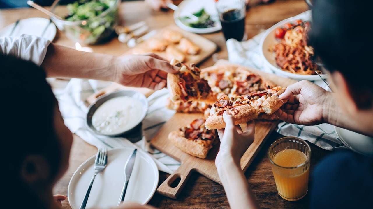 A group of friends eating slices of pizza. Next Avenue, friendship, potlucks, cooking