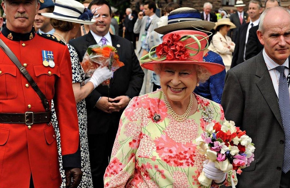 Queen Elizabeth II holding a bouquet of flowers. Next Avenue