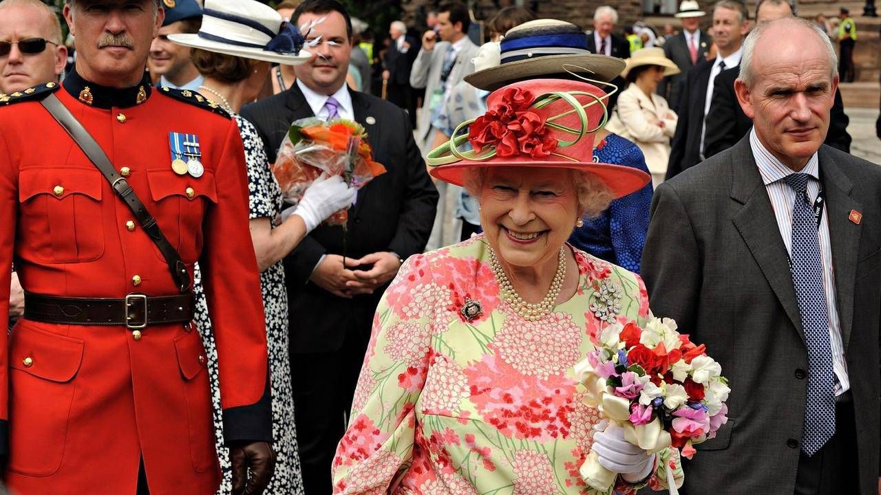 Queen Elizabeth II holding a bouquet of flowers. Next Avenue