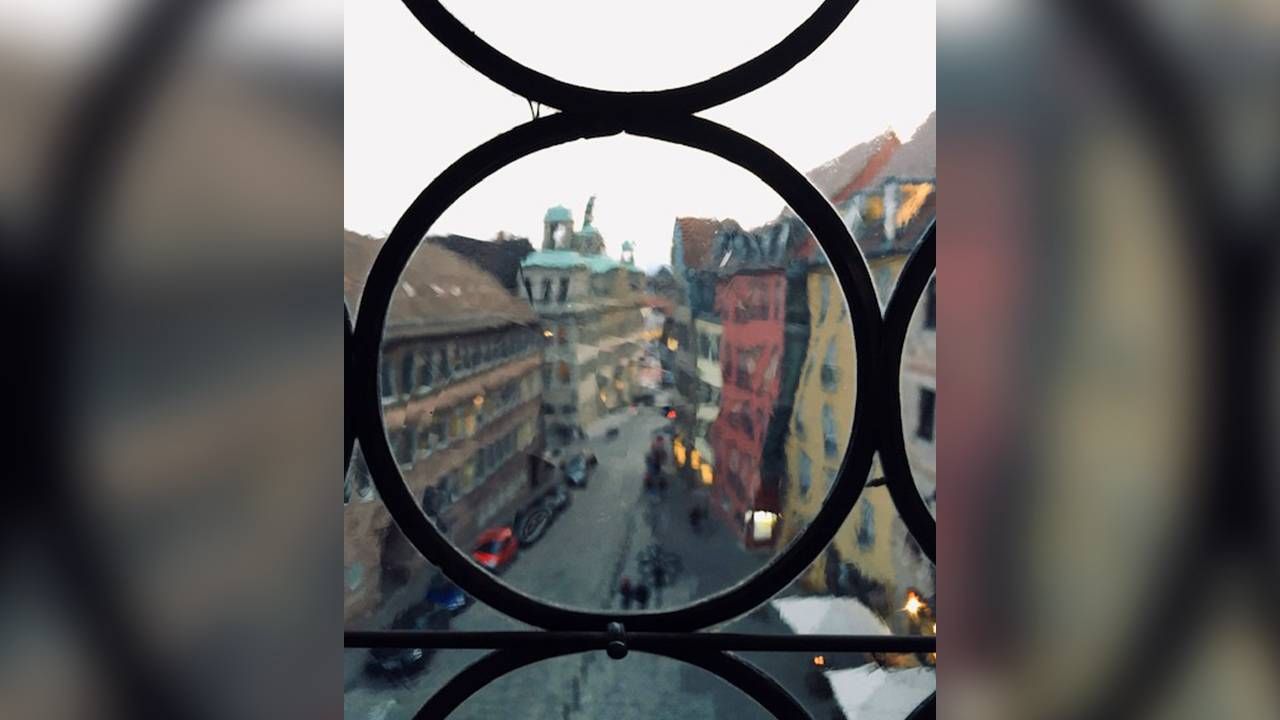 The view of a busy street in Germany clouded by an antique glass window pane. Next Avenue, travel vision visual impaired