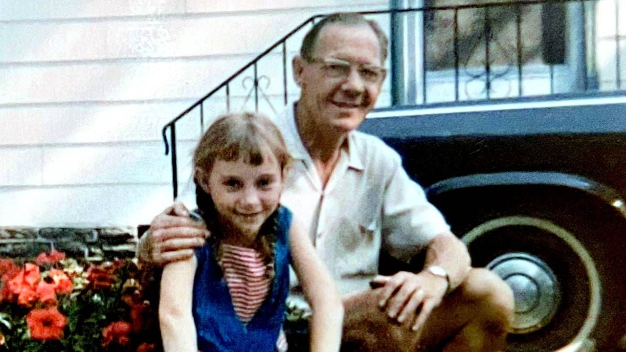 An old photo of a little girl sitting next to her dad on the front stoop. Next Avenue, dad stories
