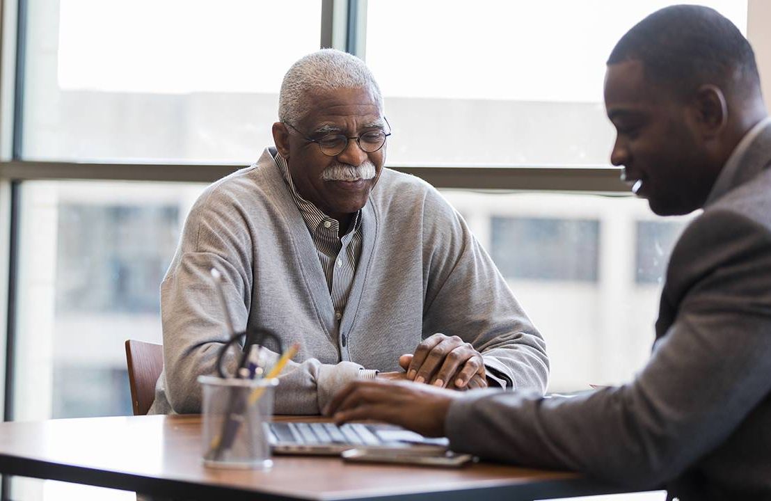 A man looking over his retirement savings plan with a financial advisor. Next Avenue
