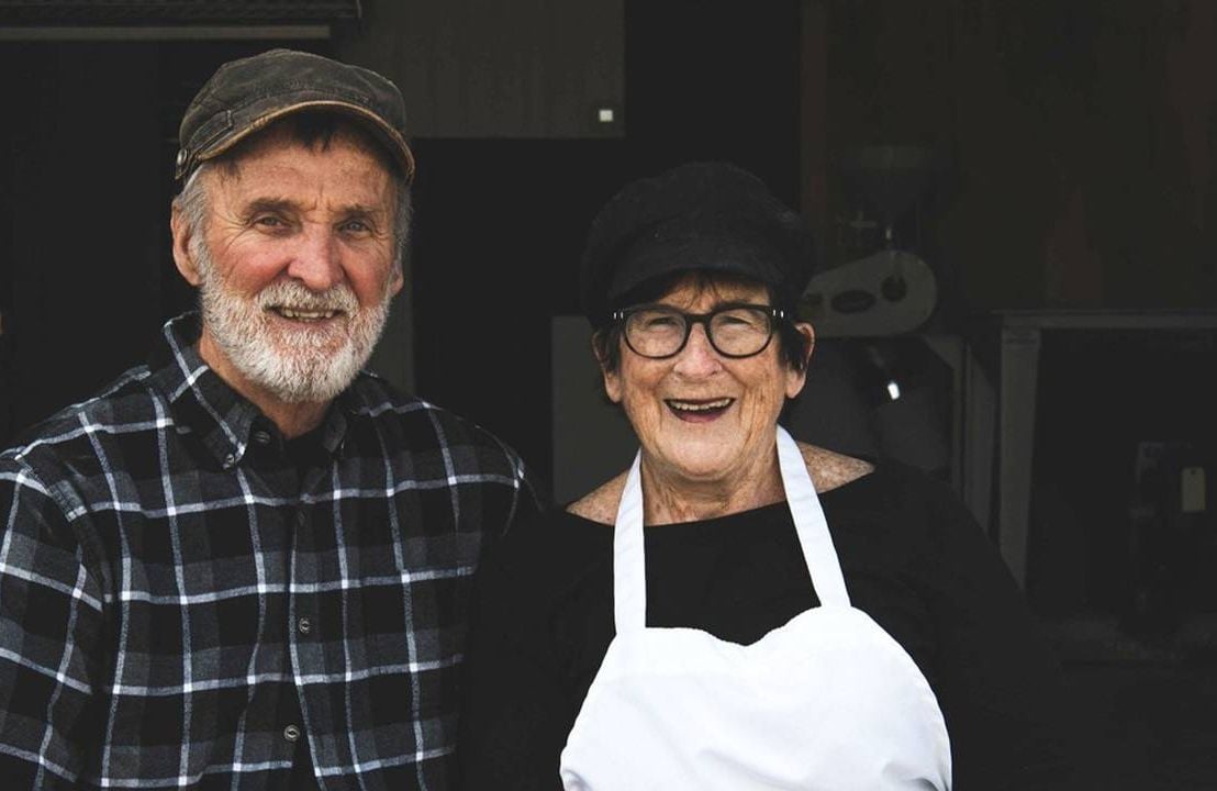 Two bakers sitting side-by-side smiling outside a flour mill. Next Avenue,