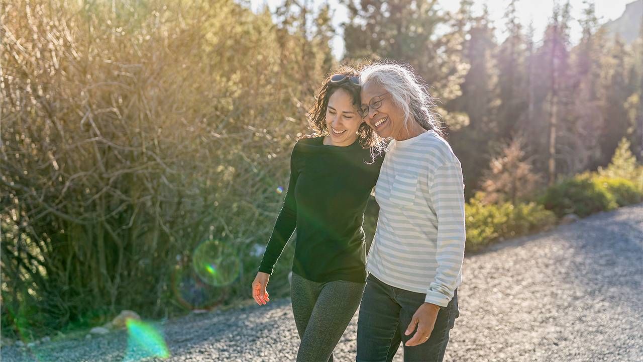 An older adult and their adult child walking together. Next Avenue