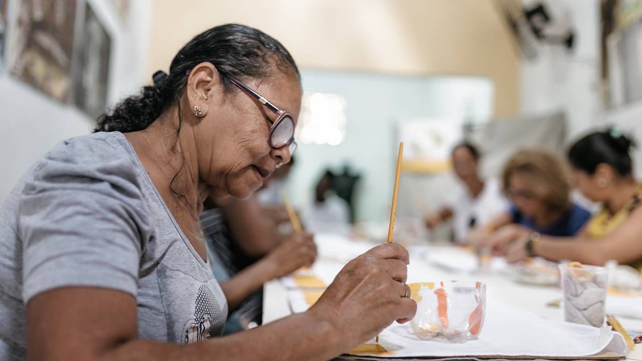 A group of older adults gathered at a third place, doing a painting group class. Next Avenue, aging solo, third places