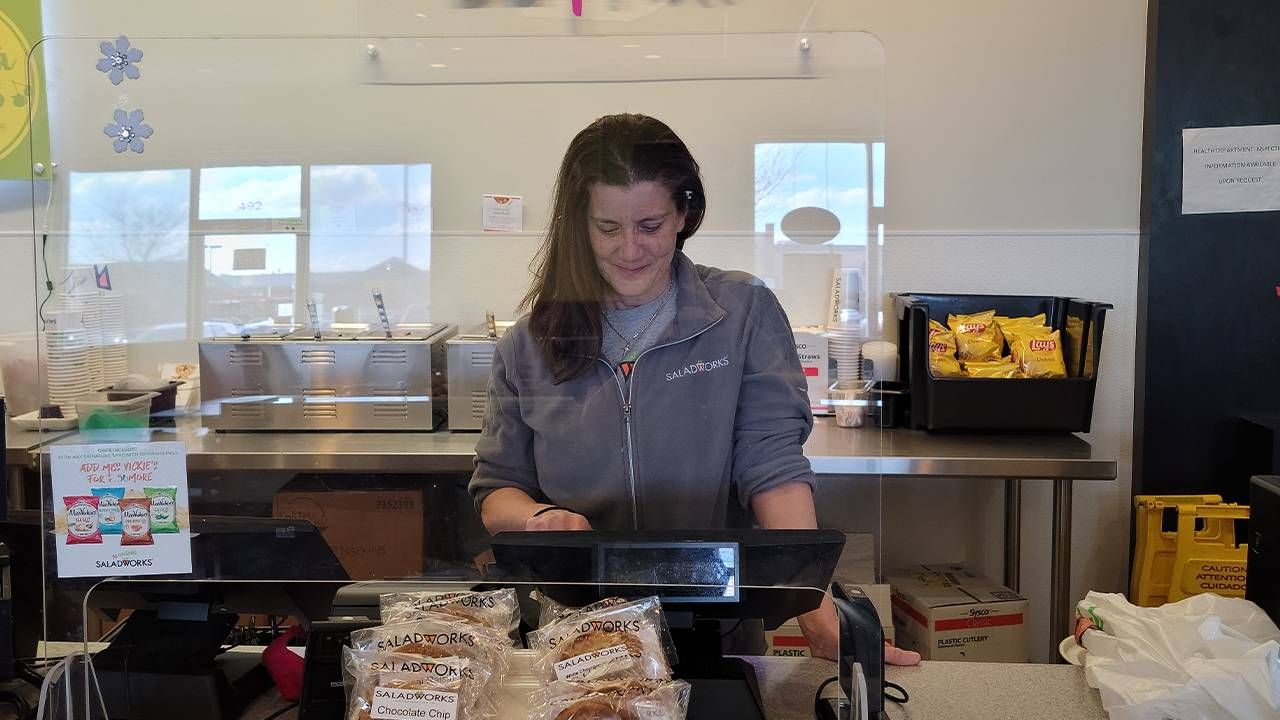 A woman standing behind the register of her business. Next Avenue, career shift stories