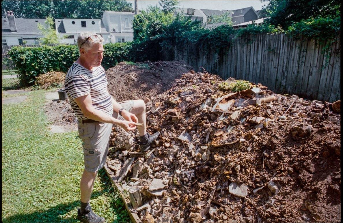 A man standing on a pile of dug up debris outside. Next Avenue, backyard treasures