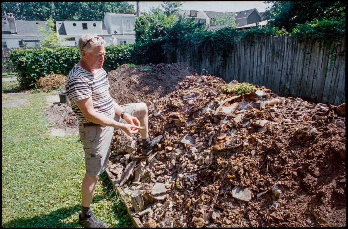 A man standing on a pile of dug up debris outside. Next Avenue, backyard treasures