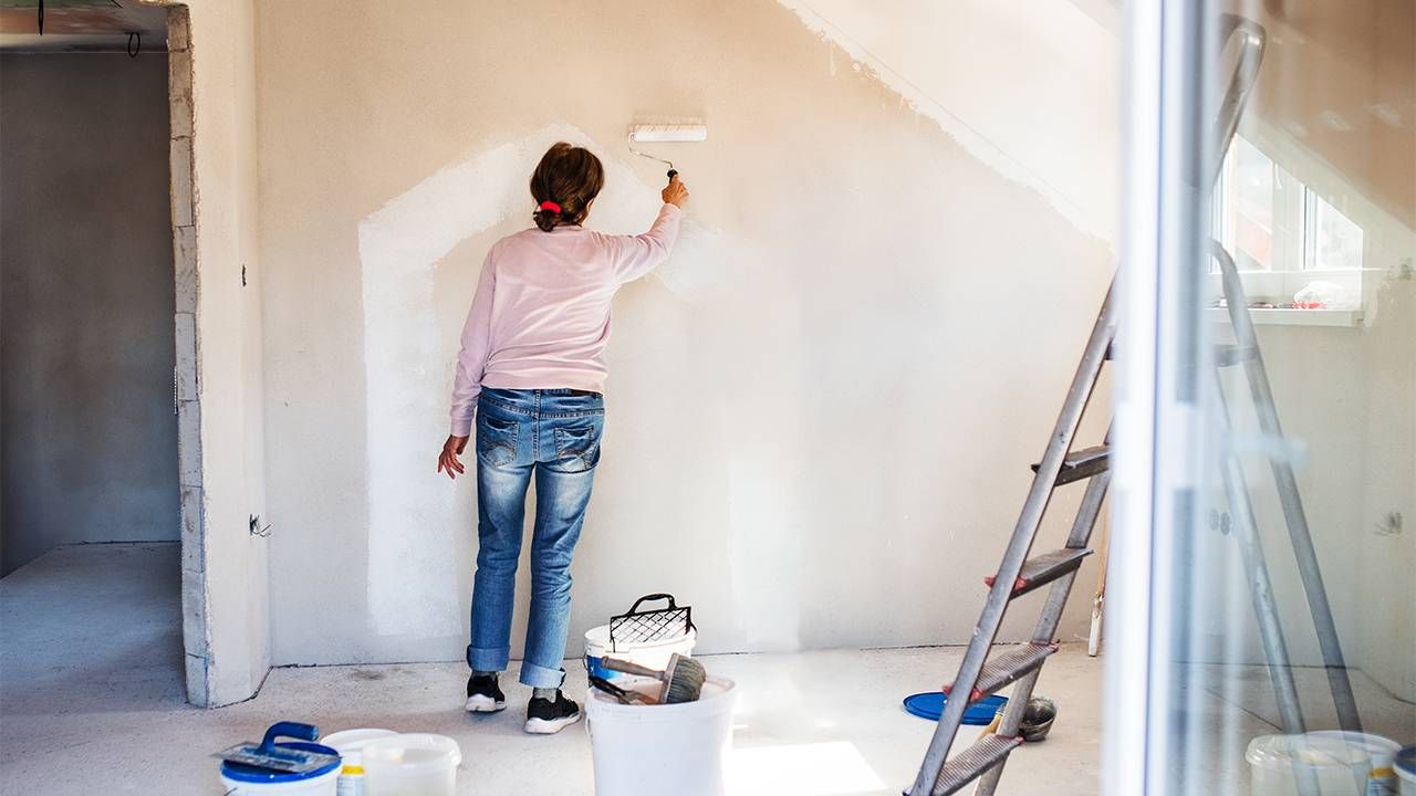 A woman painting the walls of her new house. Next Avenue, Buying a house in midlife, 50+