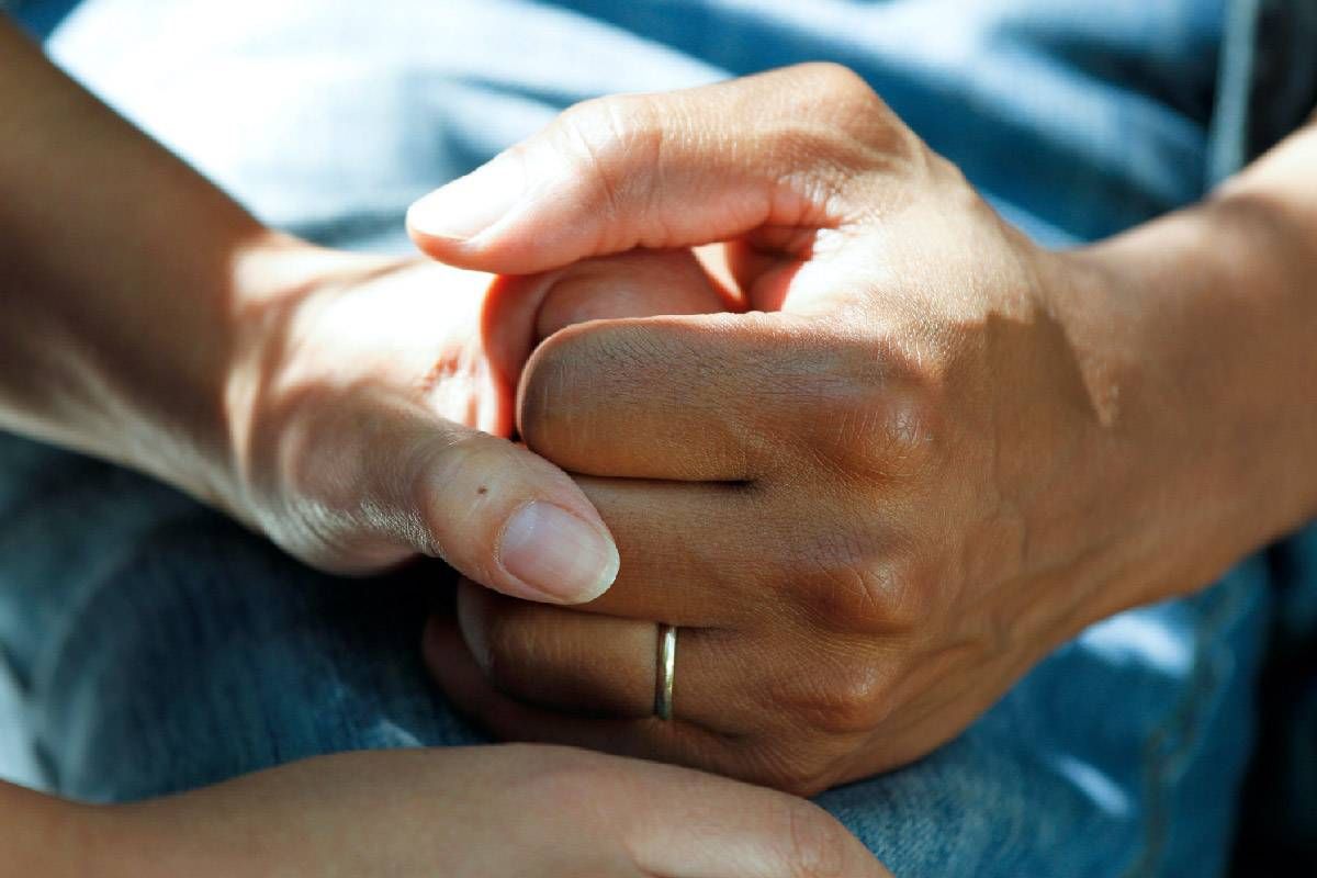 A grieving person holding another person's hand. Next Avenue, facing suicide, spouse's suicide