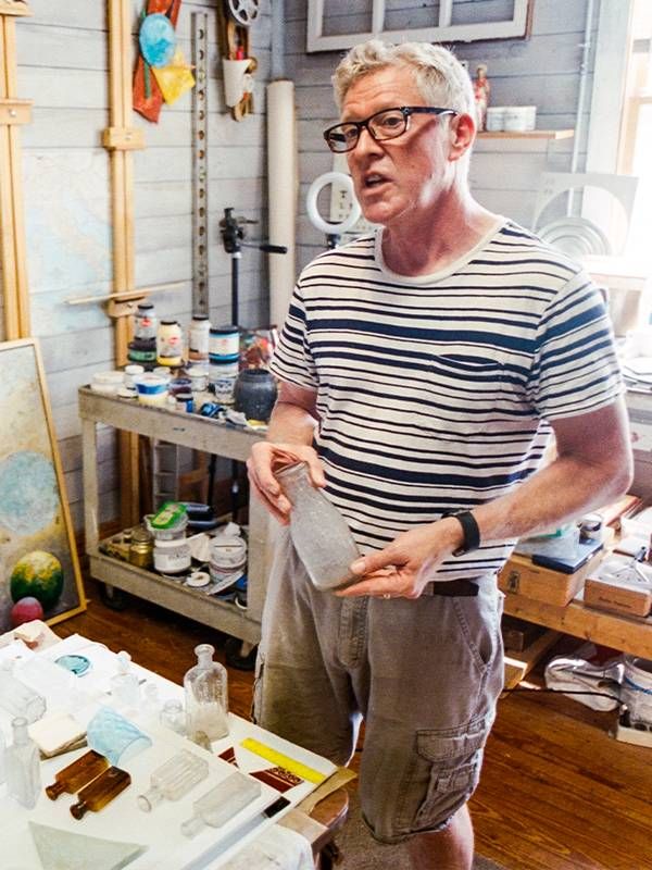 A man holding up an old glass bottle. Next Avenue, backyard treasures