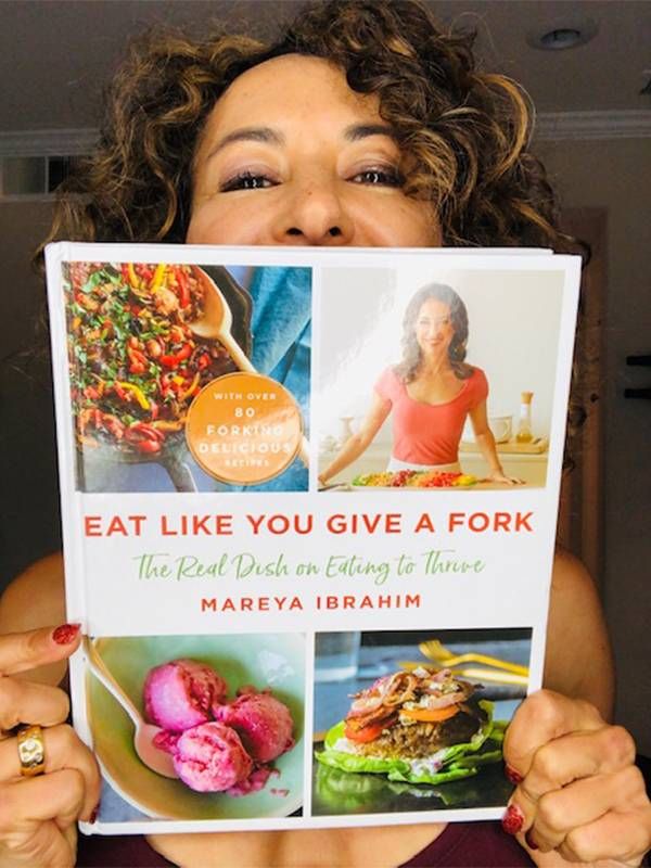 Chef Mareya Ibrahim holding up her cookbook. Next Avenue, looking good at 50