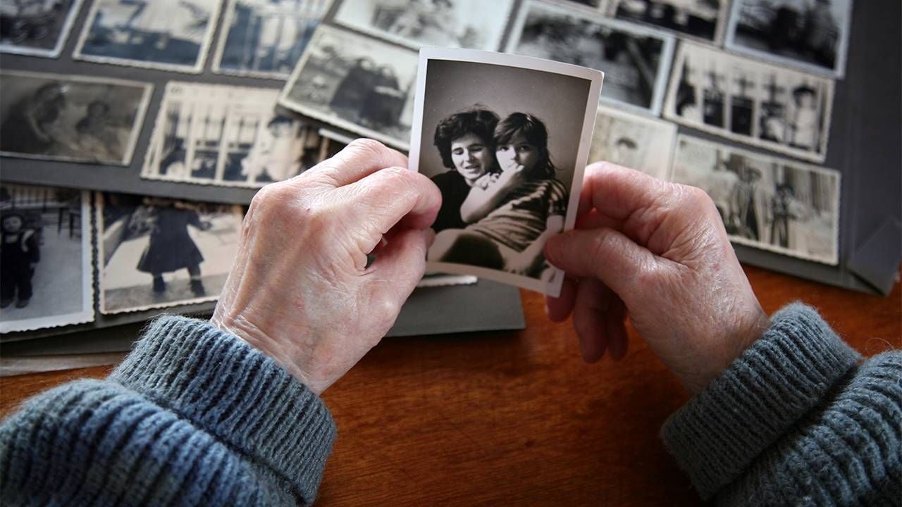 A close-up of a person's hands holding old family photos. Next Avenue, forgiving your parents