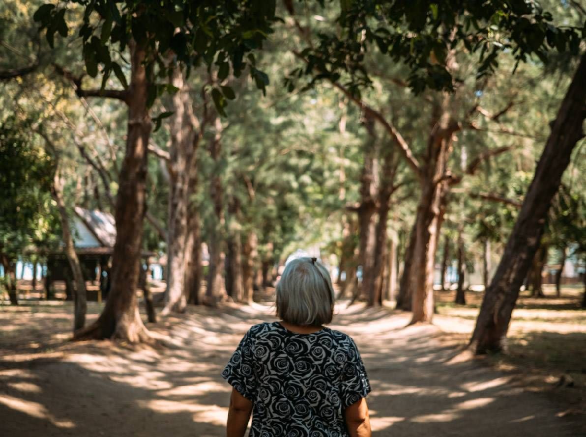 A woman walking down a tree-lined path. Next Avenue, coping with grief, learning from grief