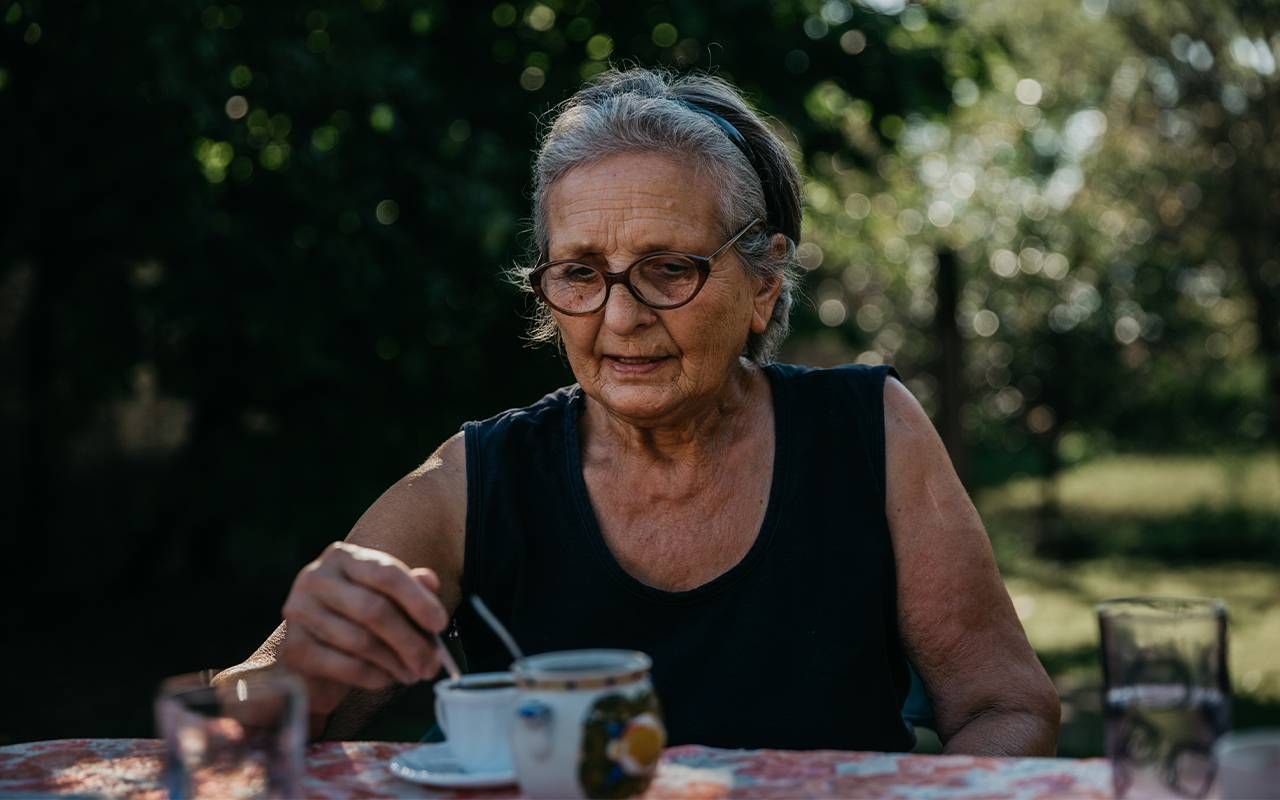 A woman drinking tea sitting outside. Next Avenue, complicated grief in older adults