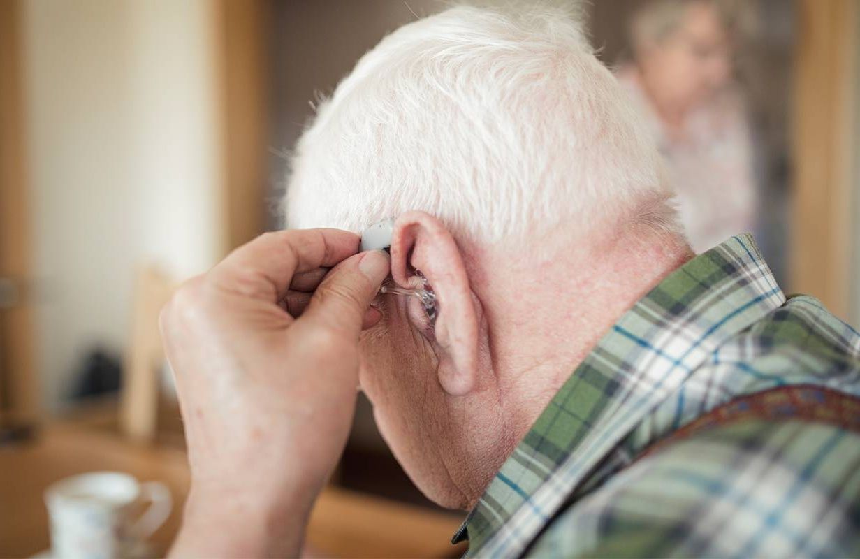 A man putting in his hearing aid. Next Avenue, Psychological impacts of hearing loss