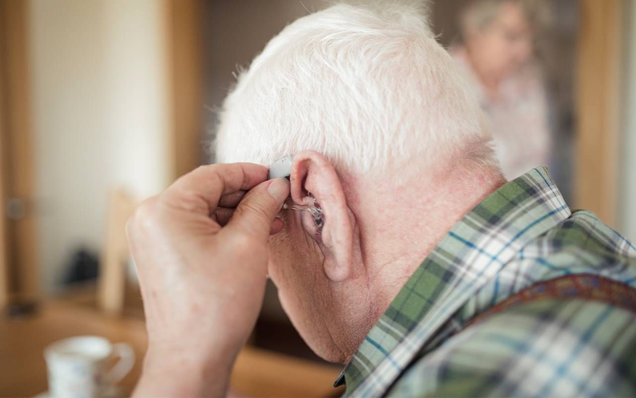 A man putting in his hearing aid. Next Avenue, Psychological impacts of hearing loss