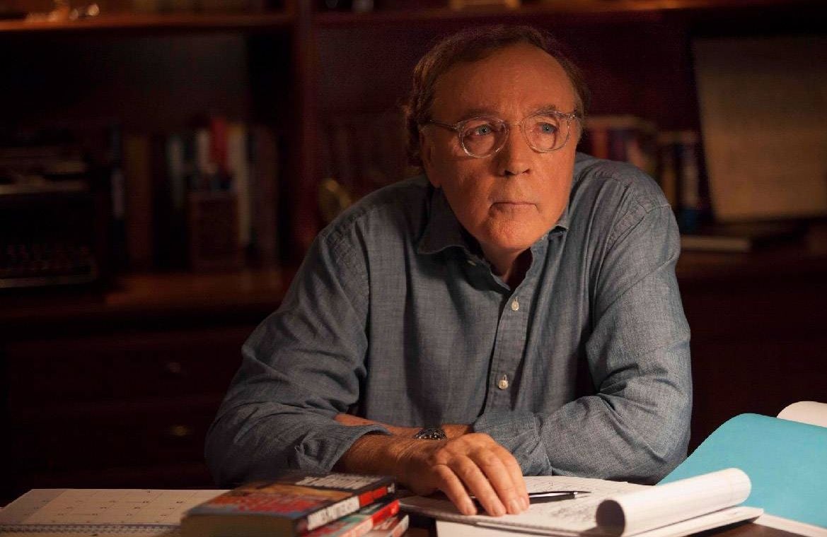 James Patterson sitting at his desk with a notepad. Next Avenue